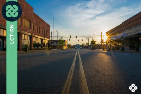 Photograph of an empty town road with sun shining.