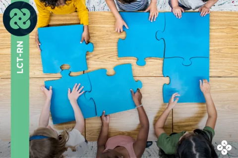 Photograph of 6 kids putting together a giant puzzle.