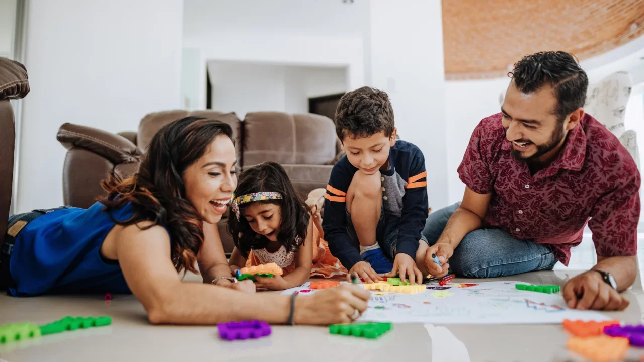 Photograph of a family drawing together on the floor of their home