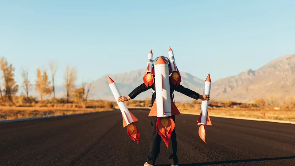 Photograph of a young child with a rocket, looking upward.