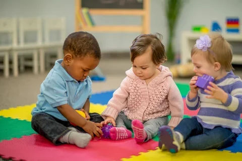 Three young children playing in a preschool.