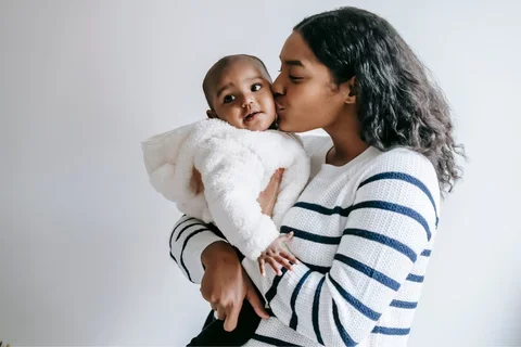 Photograph of a mother kissing her child on the cheek.