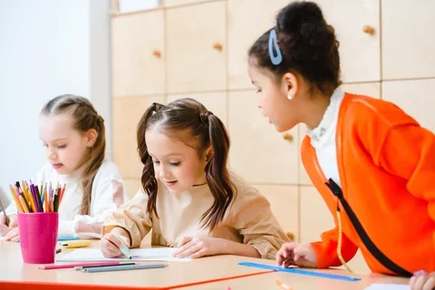 Photograph of three young girls in a classroom. 