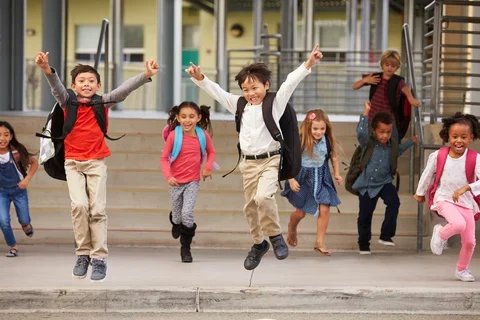 Photograph of running towards the camera in front of a school.