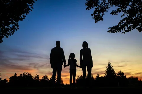 Family standing against the sunset.