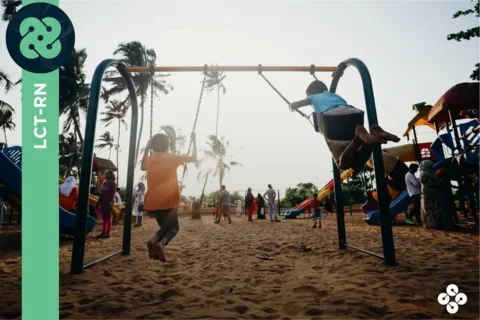 Photograph of two kids swinging on a park swingset, with the sun shining in the background.