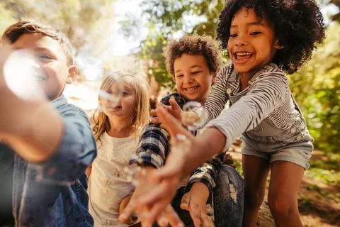 Photograph of four kids playing with bubbles while outside.
