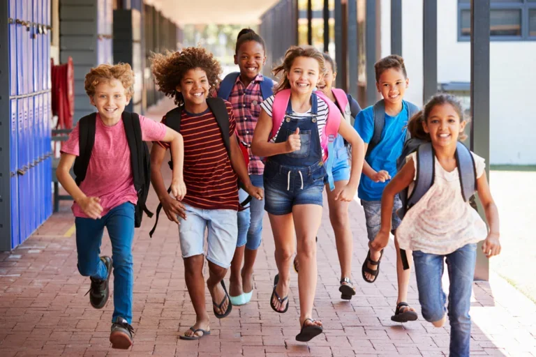  7 smiling kids running down the hallway of their school 