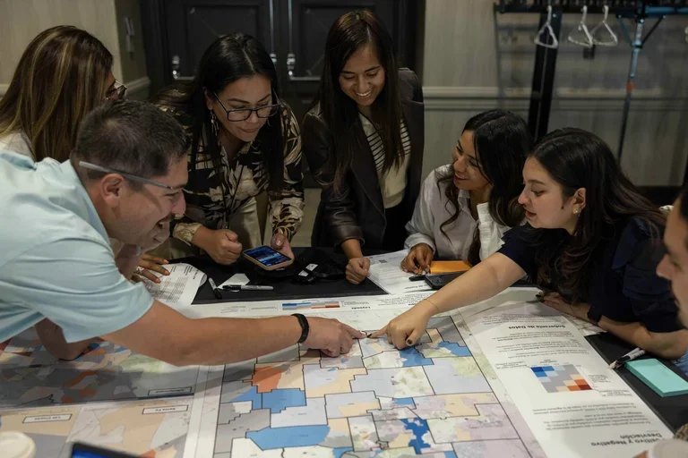 Group of people examining a poster on a table while talking.