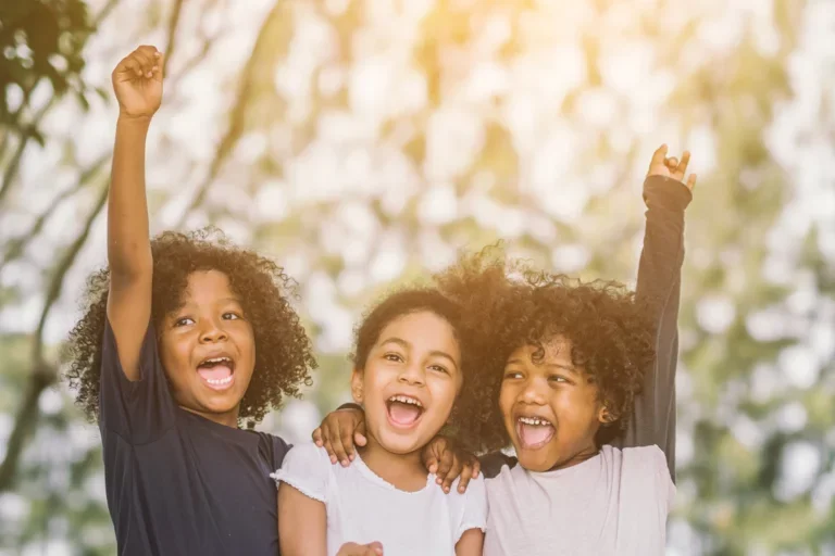 Three children smiling towards the camera
