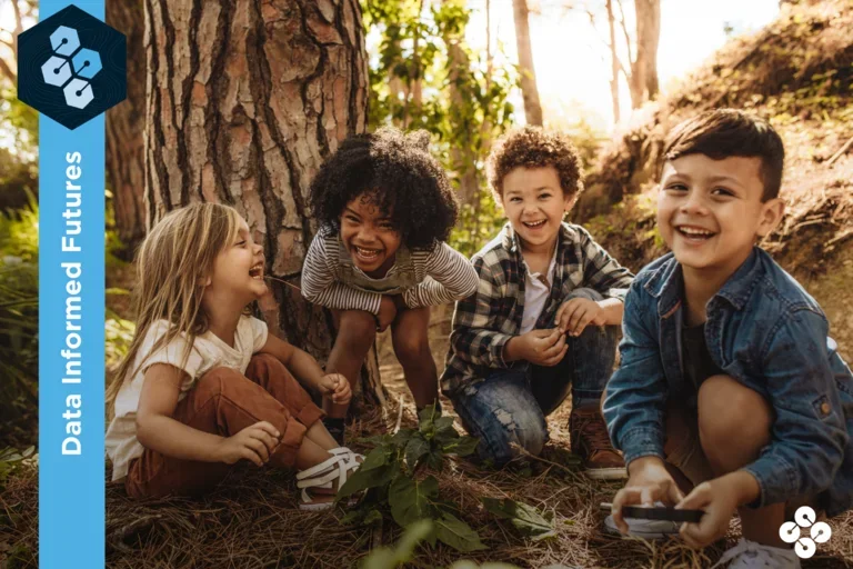Four kids playing in the woods at dusk.