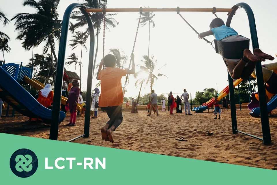 Photograph of two kids swinging on swings with their backs to the camera in the foreground. 