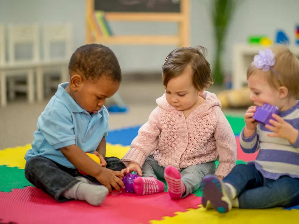 Three young children playing in a preschool.