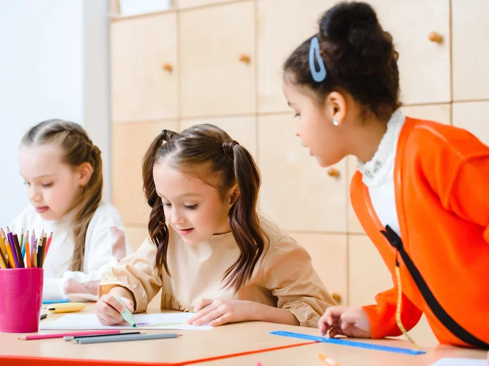 Photograph of three young girls in a classroom. 
