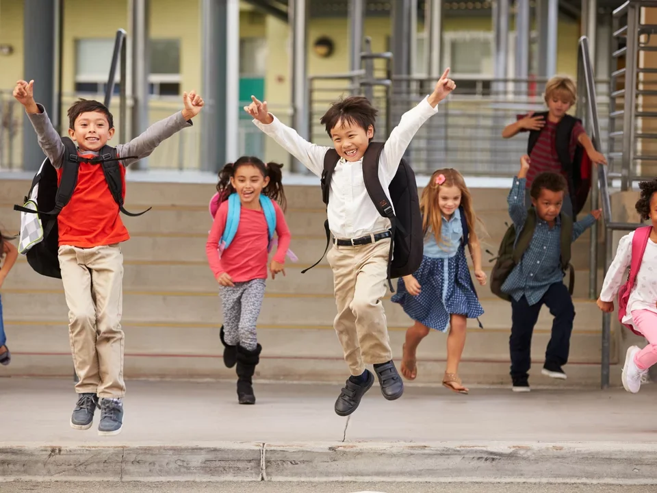 Photograph of running towards the camera in front of a school.