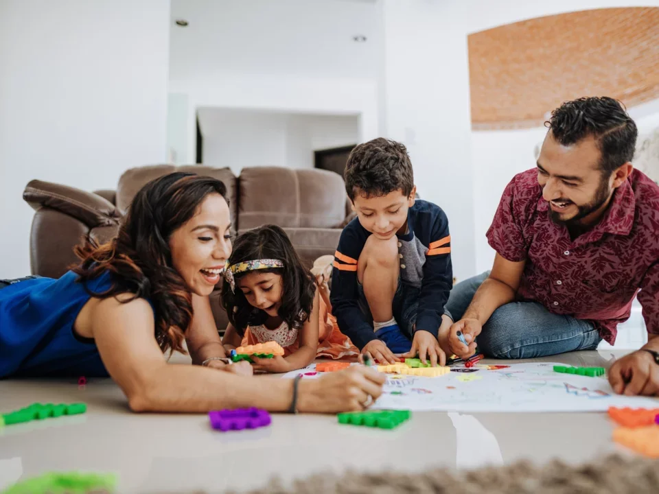 Photograph of a family drawing together on the floor of their home
