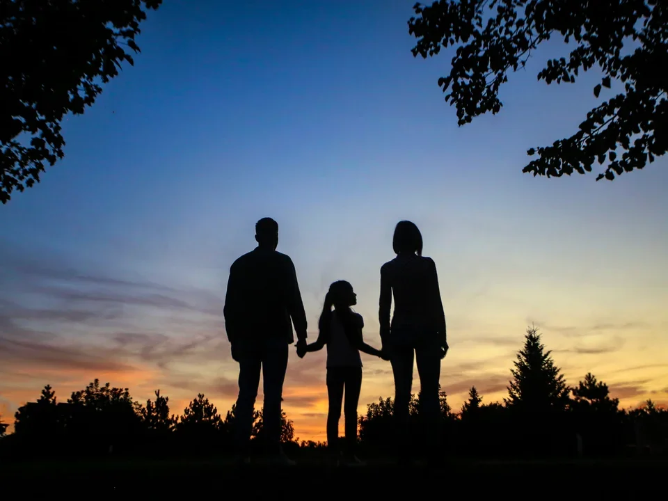 Family standing against the sunset.