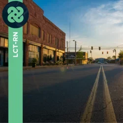 Photograph of an empty town road with sun shining.