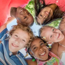 Photograph of five children huddled around a camera.